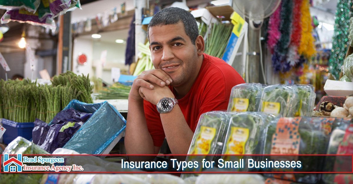 A person in a red shirt smiles behind a counter of fresh produce at a market