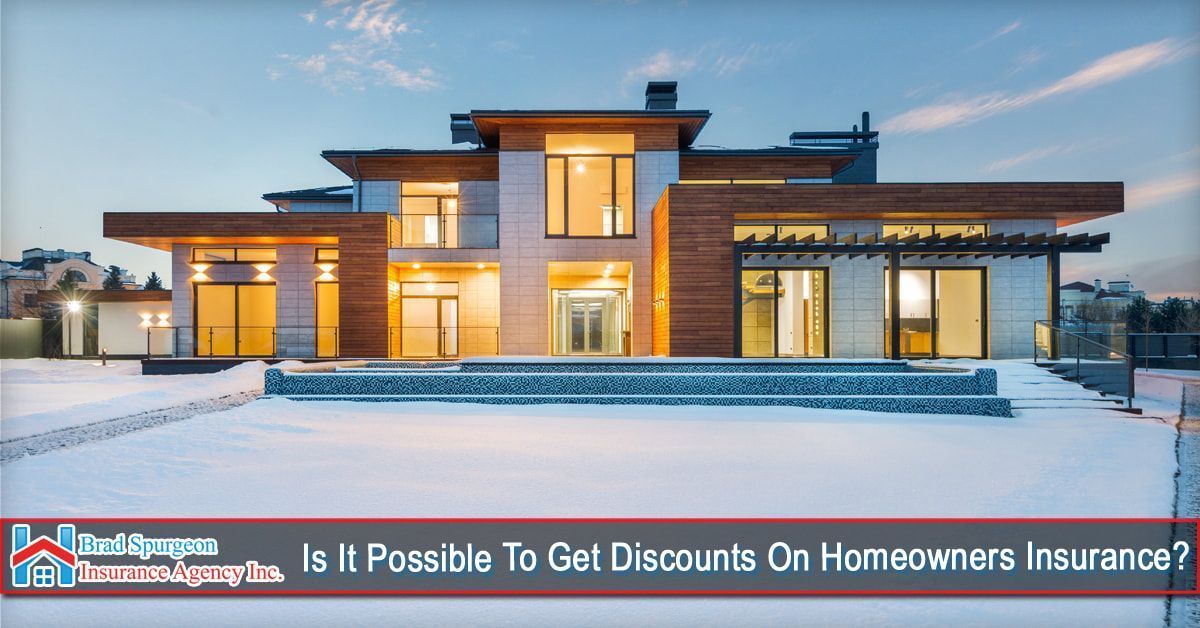 A modern, multi-story house at dusk, surrounded by snow