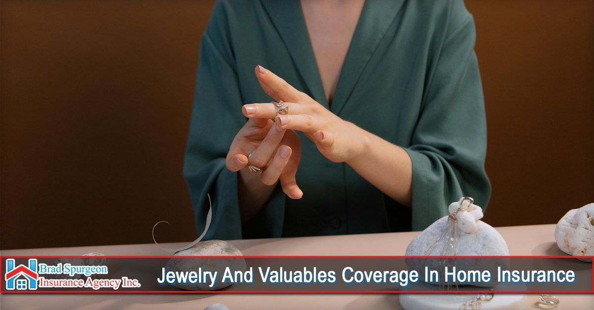 A person wearing a green robe adjusts a ring on their finger, with jewelry visible on a table 