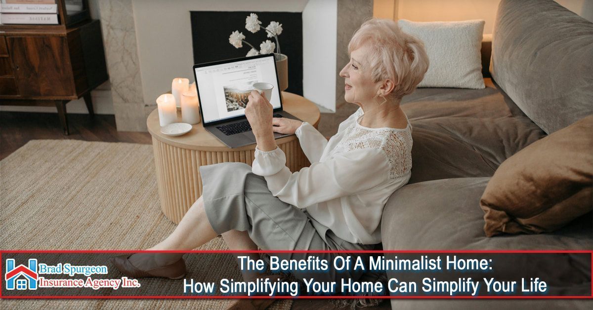 A person sits on a rug by a sofa, using a laptop on a small round table with candles in a bright, minimalist room.