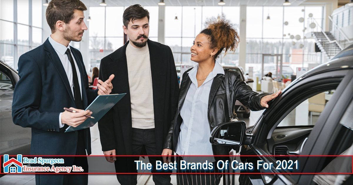A salesperson talks to two customers at a car dealership next to a vehicle