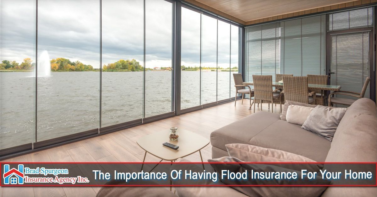 A sunroom with a table and couch overlooks a lake with a fountain, highlighting the need for flood insurance.