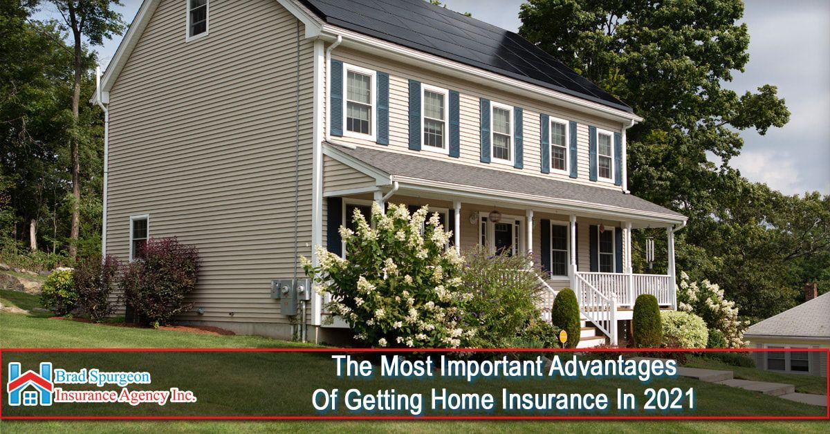 A two-story tan house with a front porch and solar panels