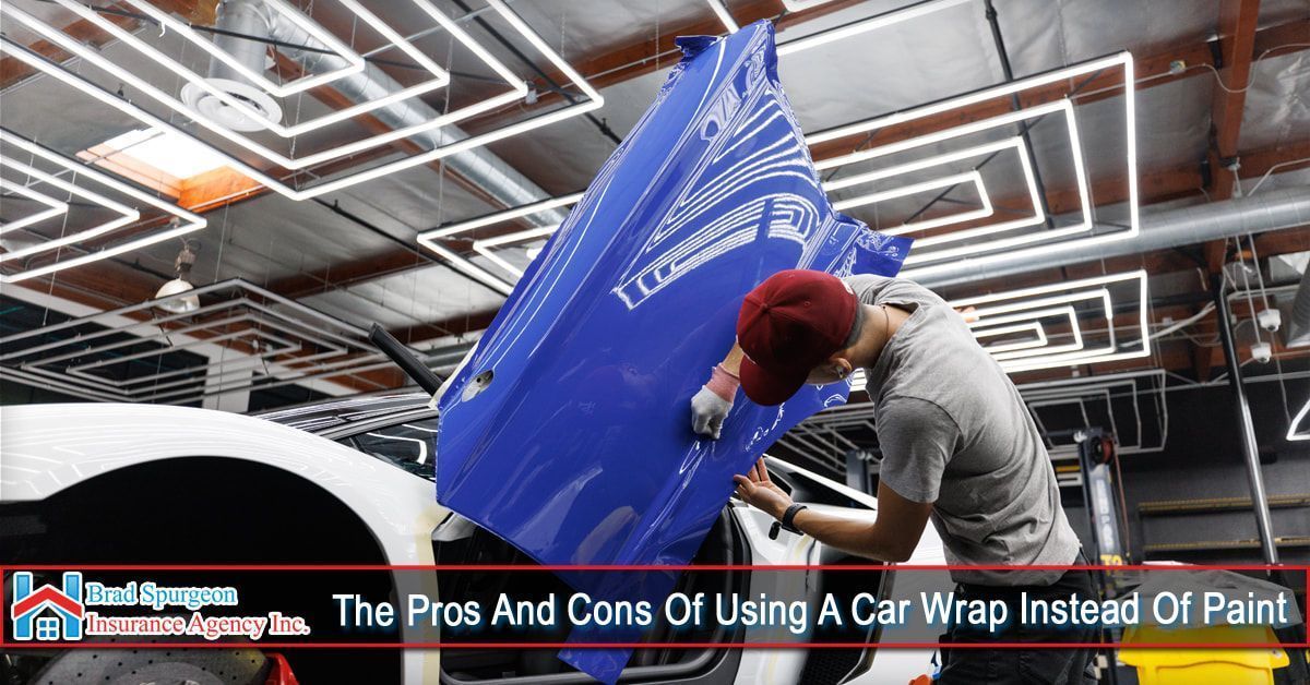 A technician applies a bright blue wrap to a car panel in a workshop