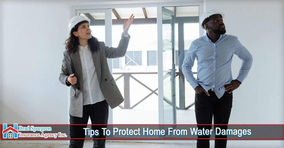 Two people wearing hard hats inspect a room with white walls
