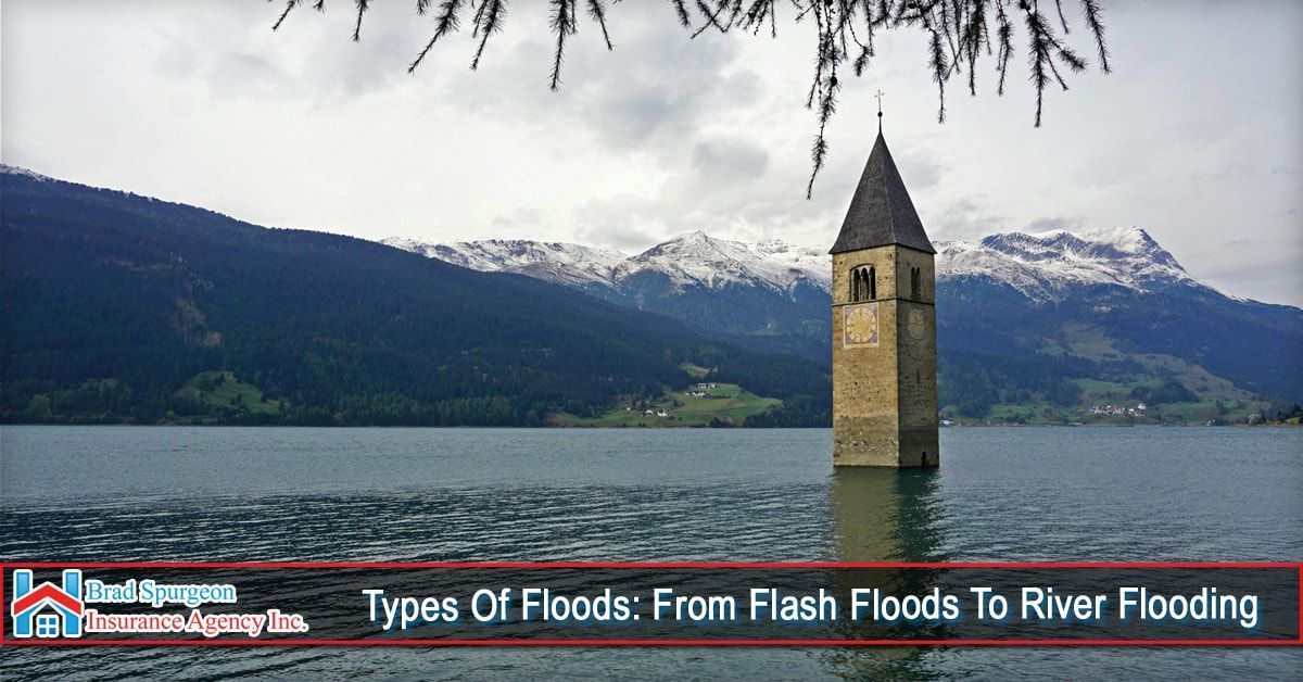 The lone stone bell tower of Curon protrudes from Lake Resia in Italy, set against snow-capped mountains.