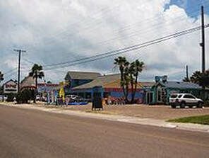 Buildings along a road with a cloudy sky. Some buildings appear to be businesses or restaurants.