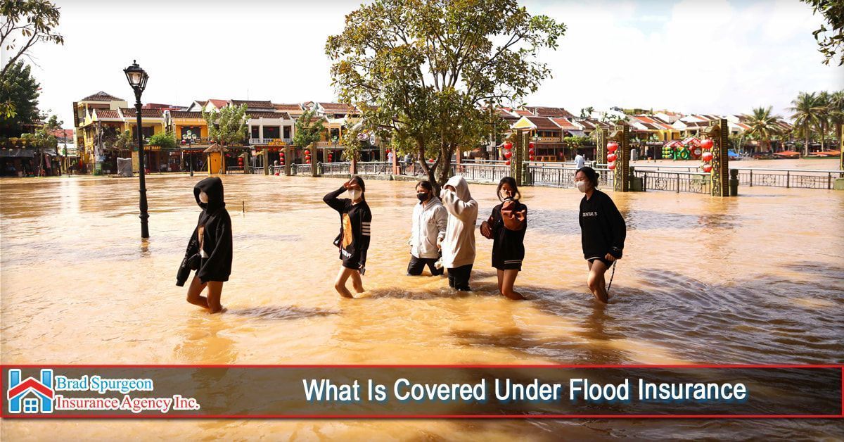 Several people wade through murky floodwaters in a town square