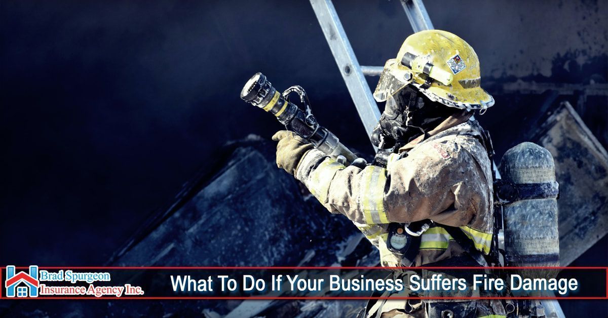 A firefighter in protective gear sprays water on a smoldering fire.