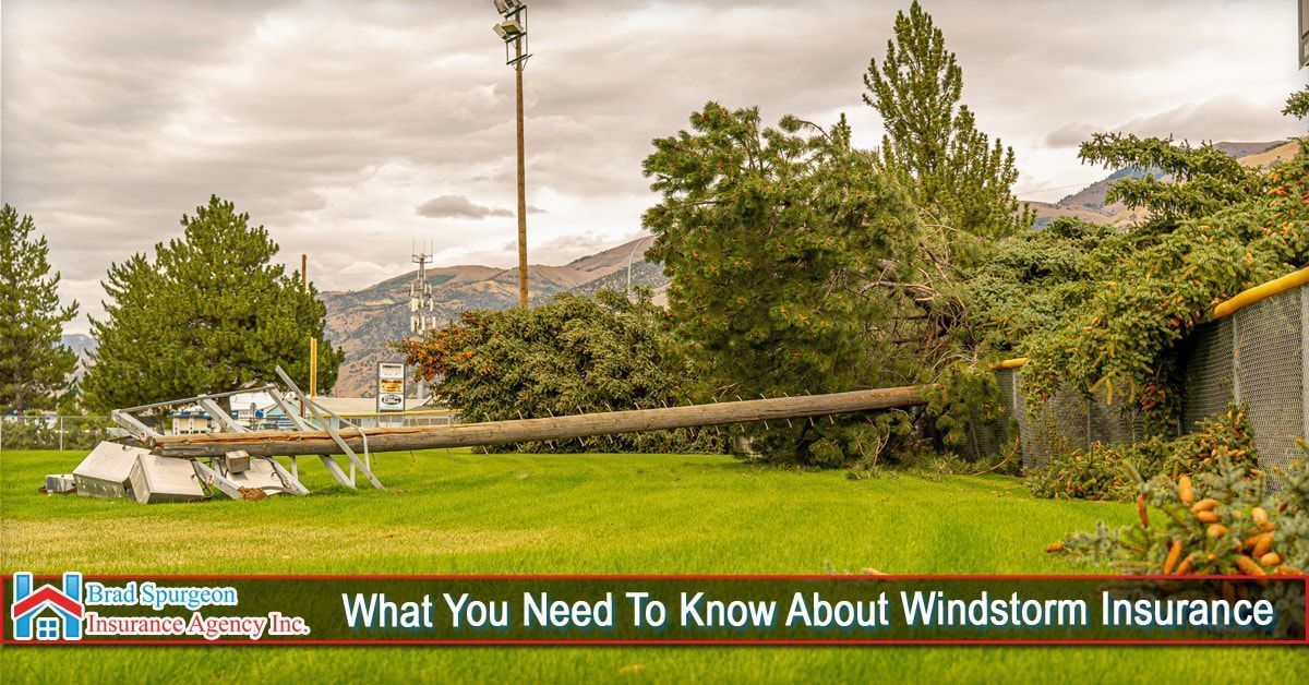 A utility pole lies broken on a grassy field, next to a damaged chain-link fence, under a cloudy sky.