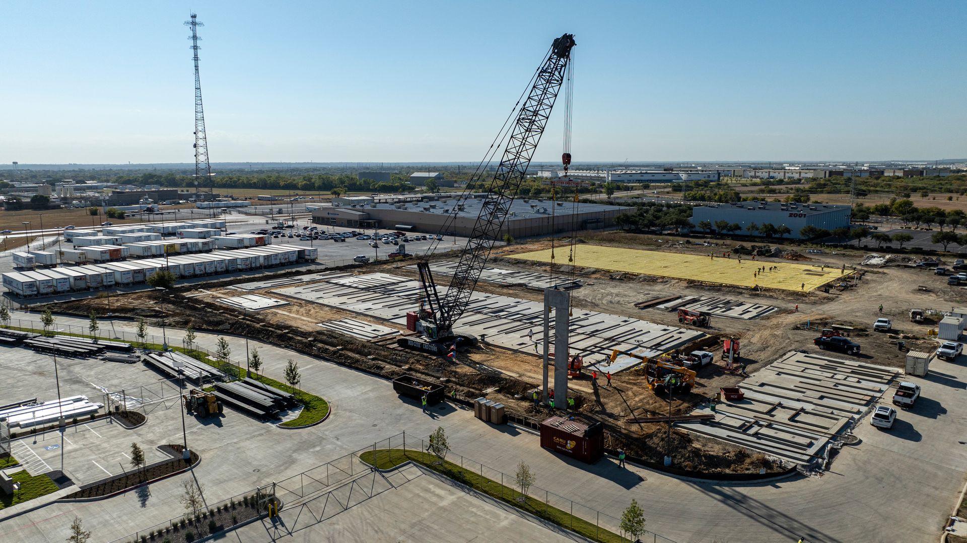 An aerial view of a concrete construction site with a large crane in the middle