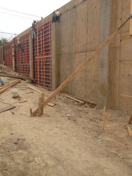 A group of construction workers are working on a cast in place concrete wall.