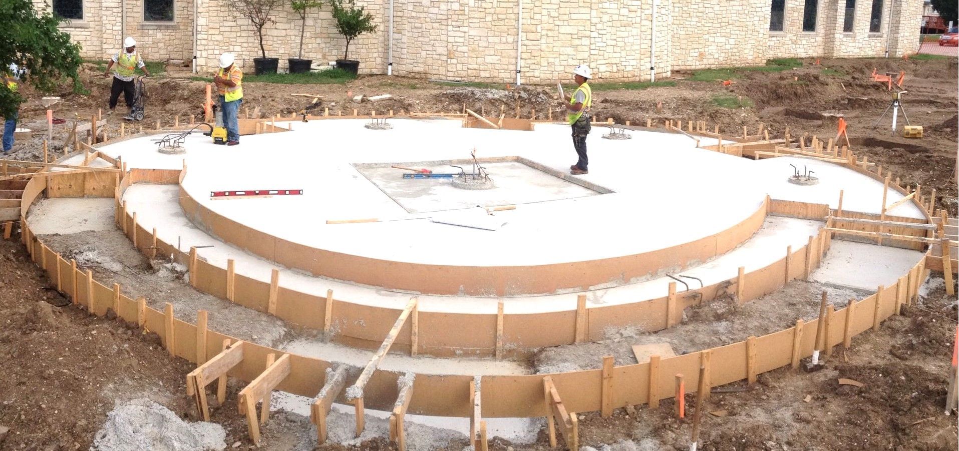 A group of construction workers are working on a large circular concrete structure