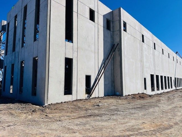 A large concrete building with tilt wall panels under construction with a lot of windows