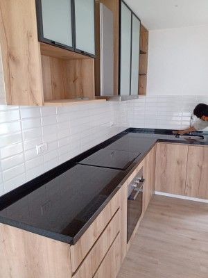 Baño minimalista de color beige con azulejos de piedra en las paredes, iluminación empotrada y lavabo blanco.