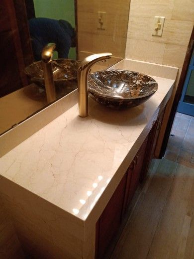 Banco minimalista de madera con tablero claro y dos soportes de madera oscura, apoyado contra una pared lisa.