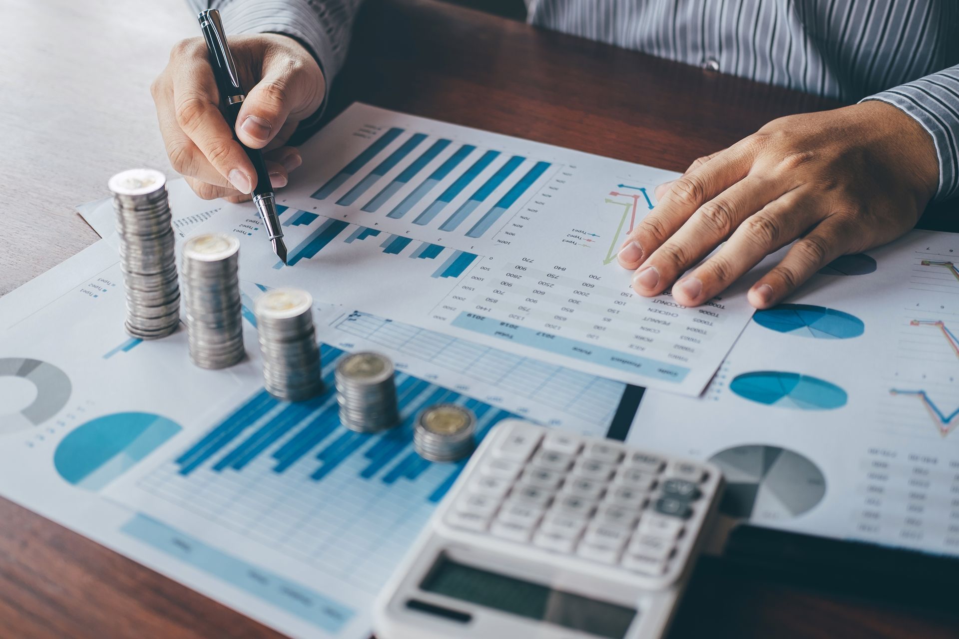 A man is sitting at a table with a calculator and stacks of coins.