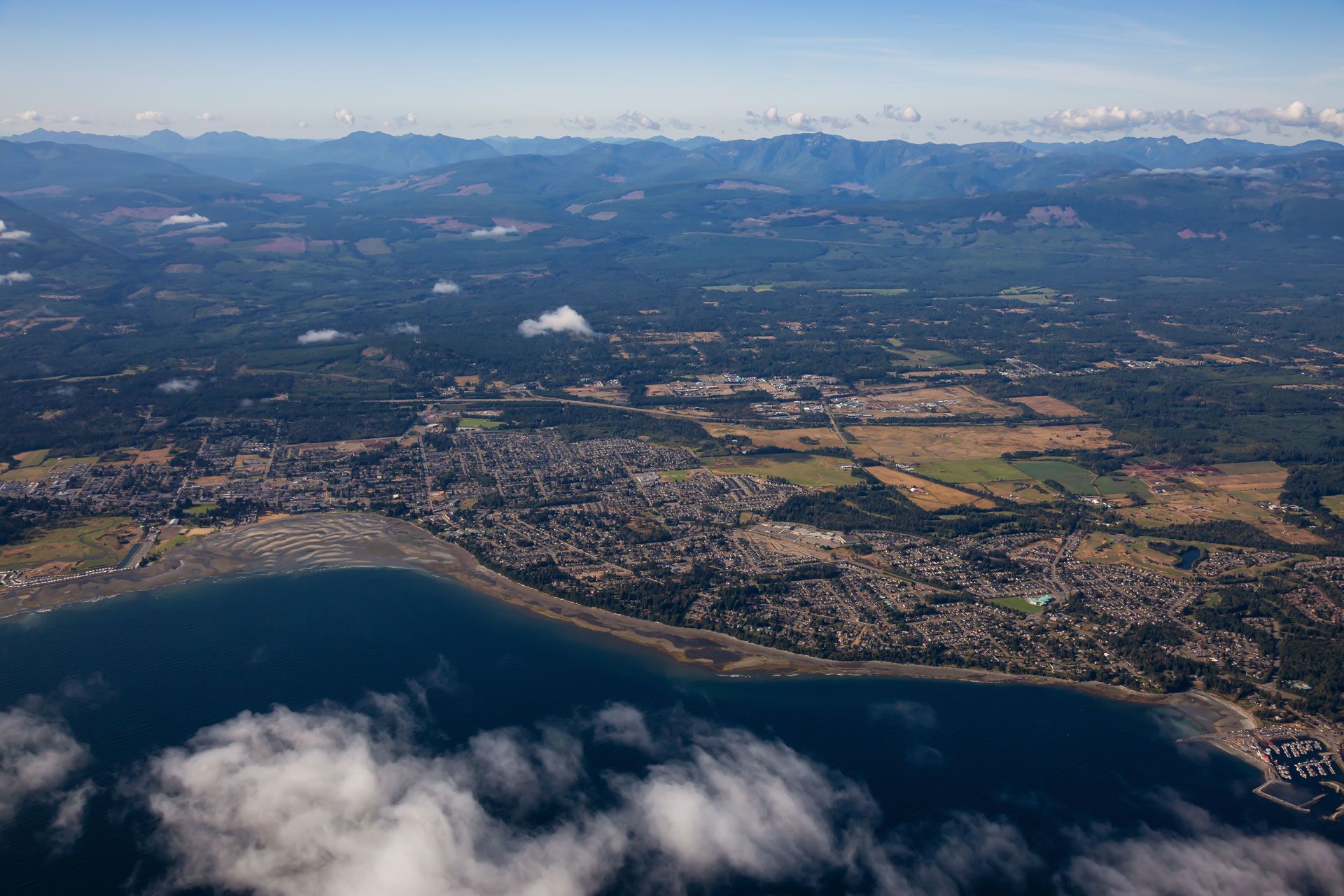 Three women smiling, standing in front of a weathered gray wooden fence.