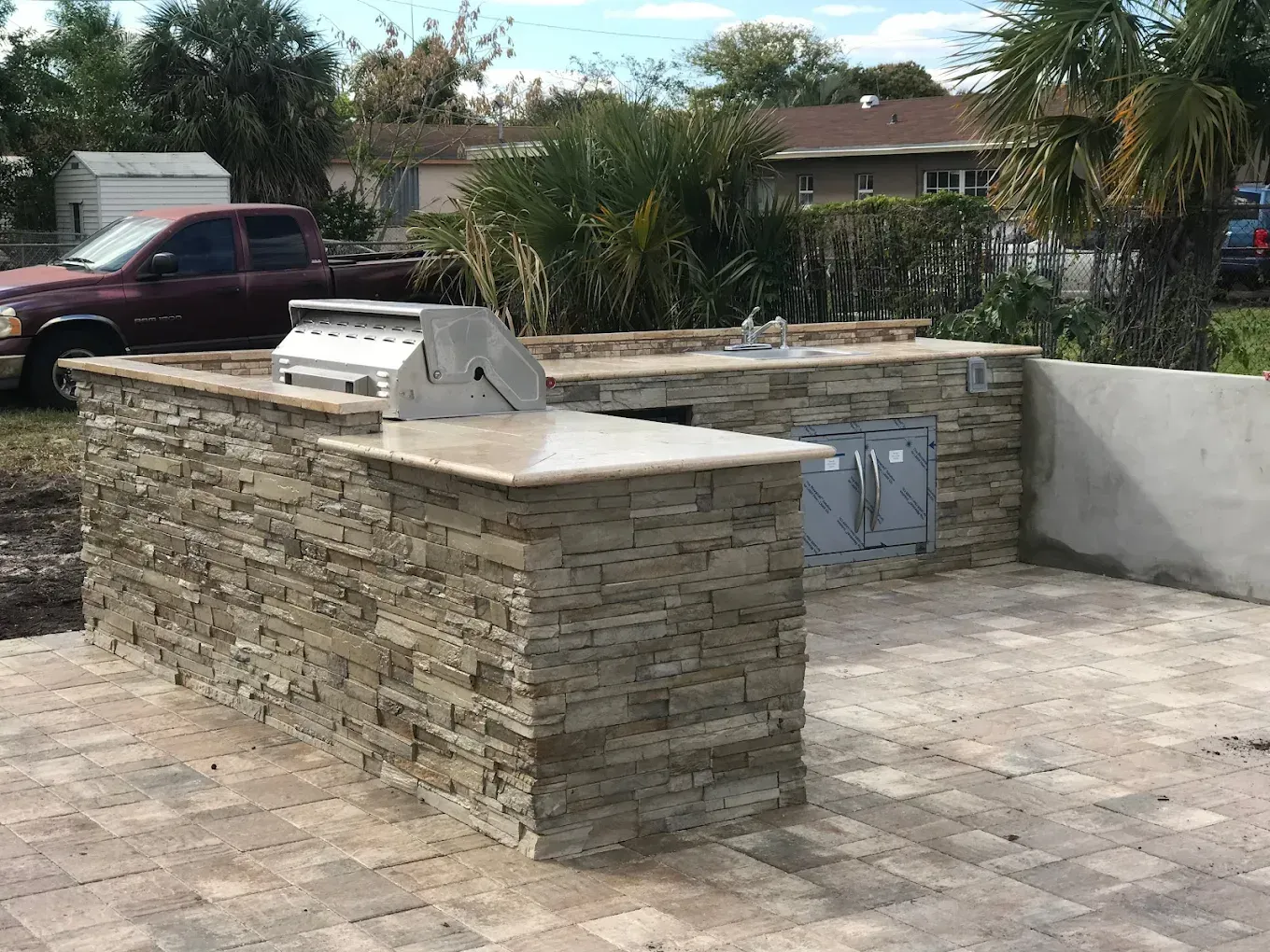 Close-up of interlocking gray concrete pavers being installed on a bed of gravel.
