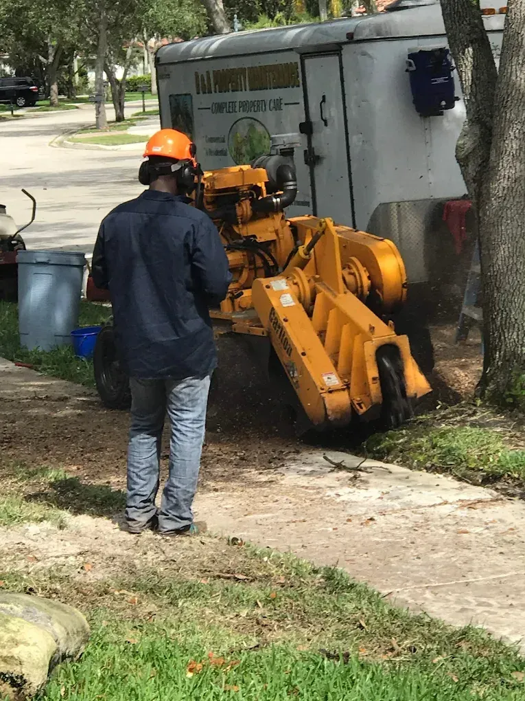 Hands in red gloves laying grey pavers with a yellow string line.