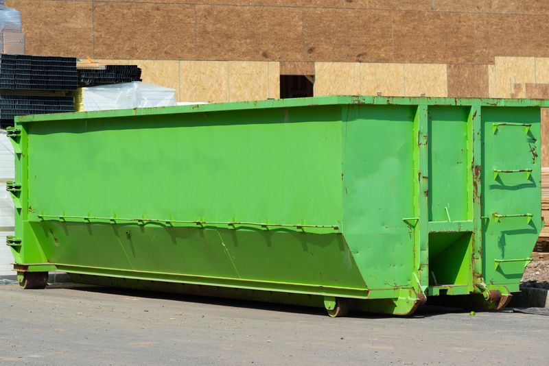 a large green dumpster is parked in front of a building .