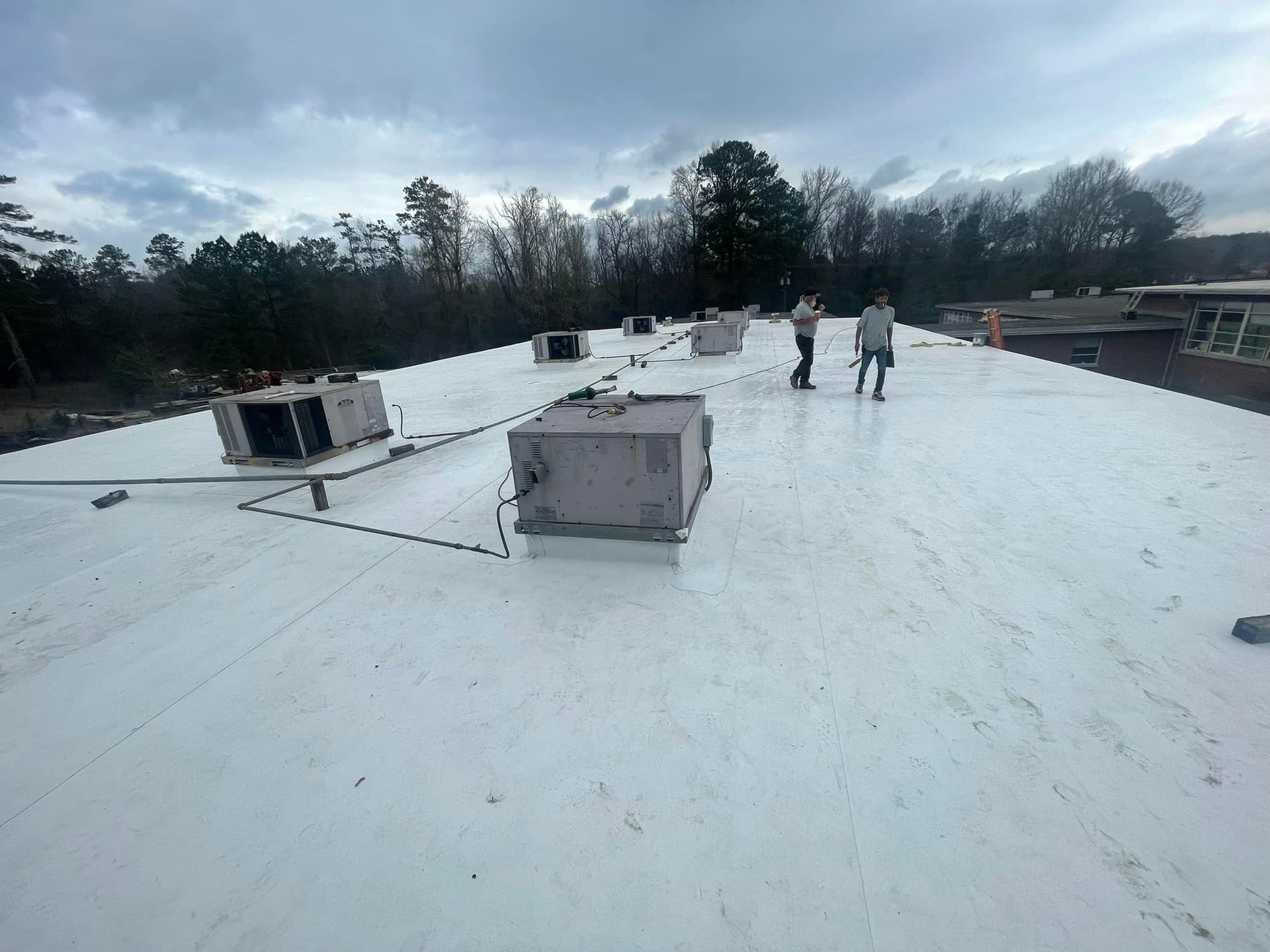 Two people are standing on top of a white roof.