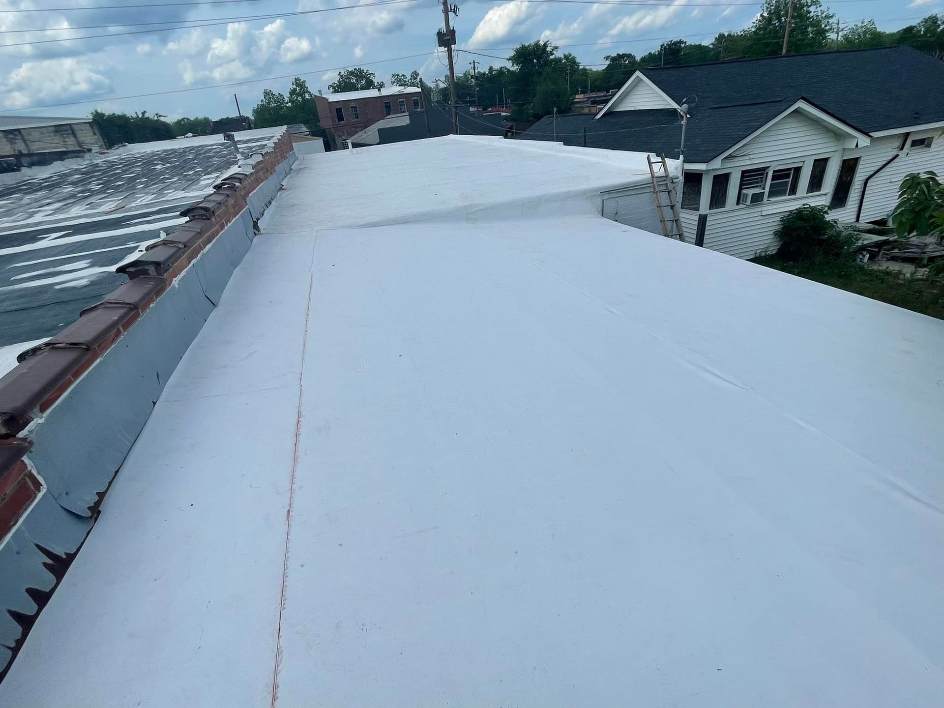 A white roof with a row of houses in the background.