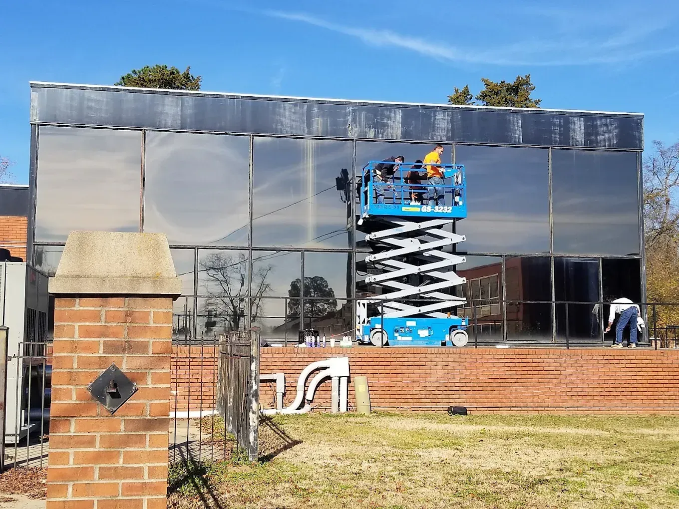 A man on a scissor lift is cleaning the windows of a building.