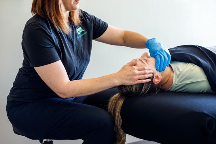 A woman is giving a massage to a patient laying on a table.