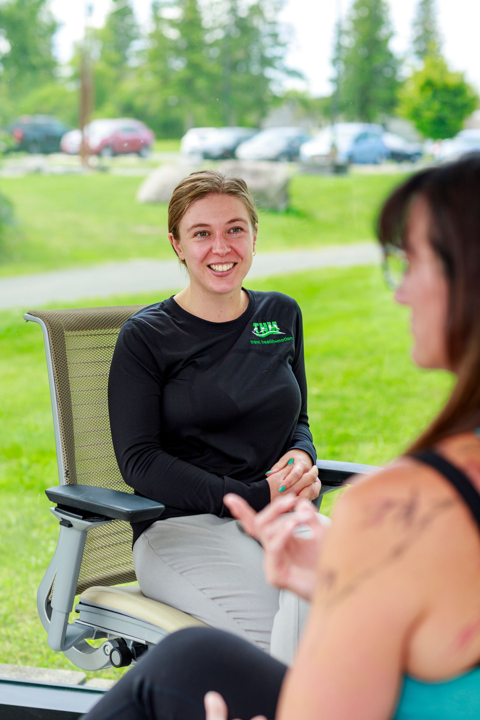A woman is sitting in a chair talking to another woman.