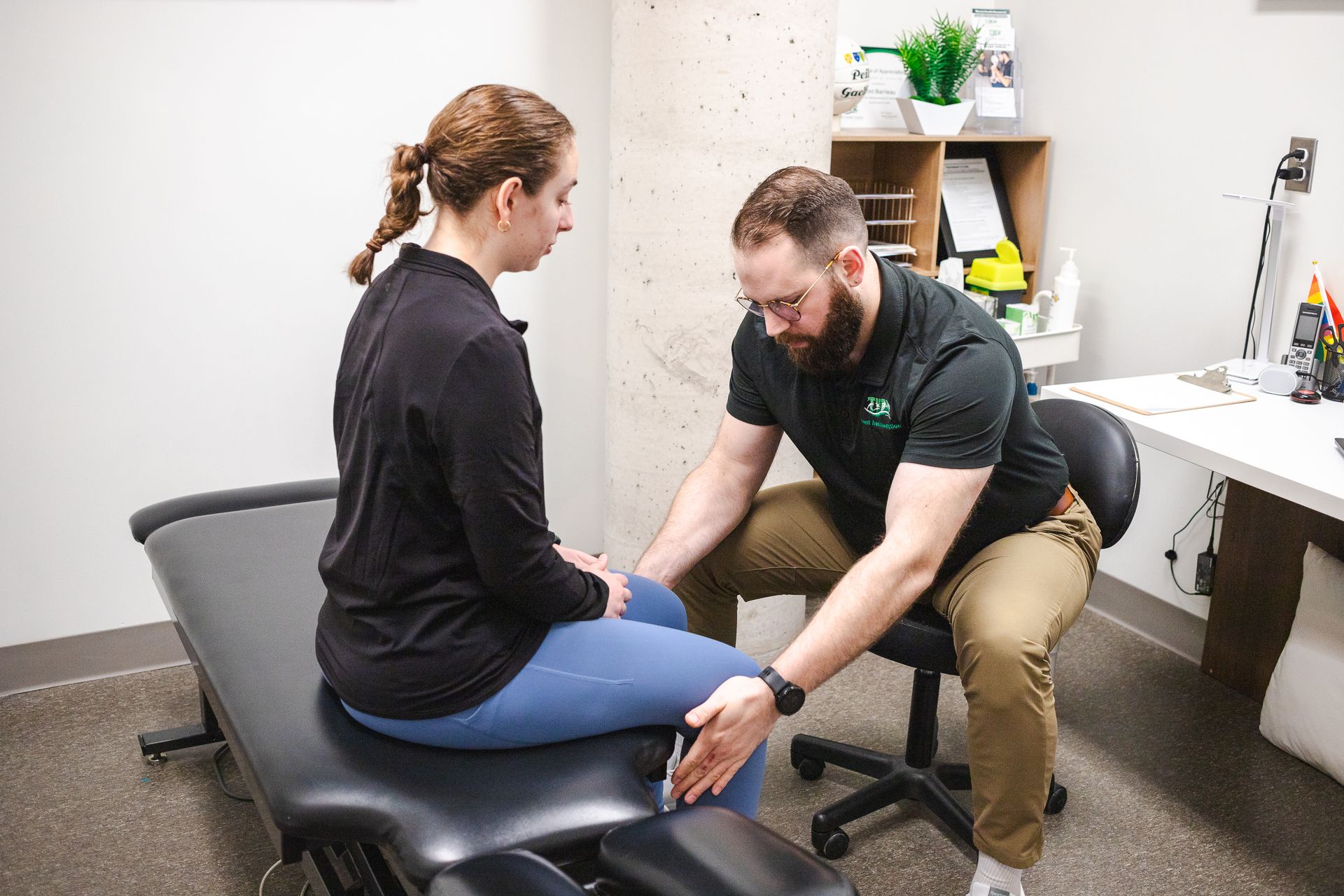 A man is stretching a woman 's back on a table.