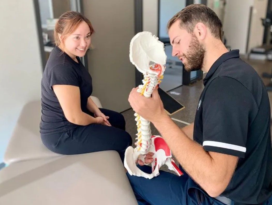 A man and a woman are looking at a skeleton model.