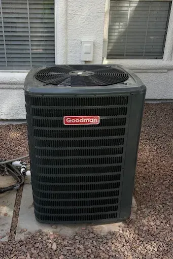 Goodman outdoor air conditioner unit beside a house wall and windows