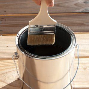 Paint brush going in a pot of black paint