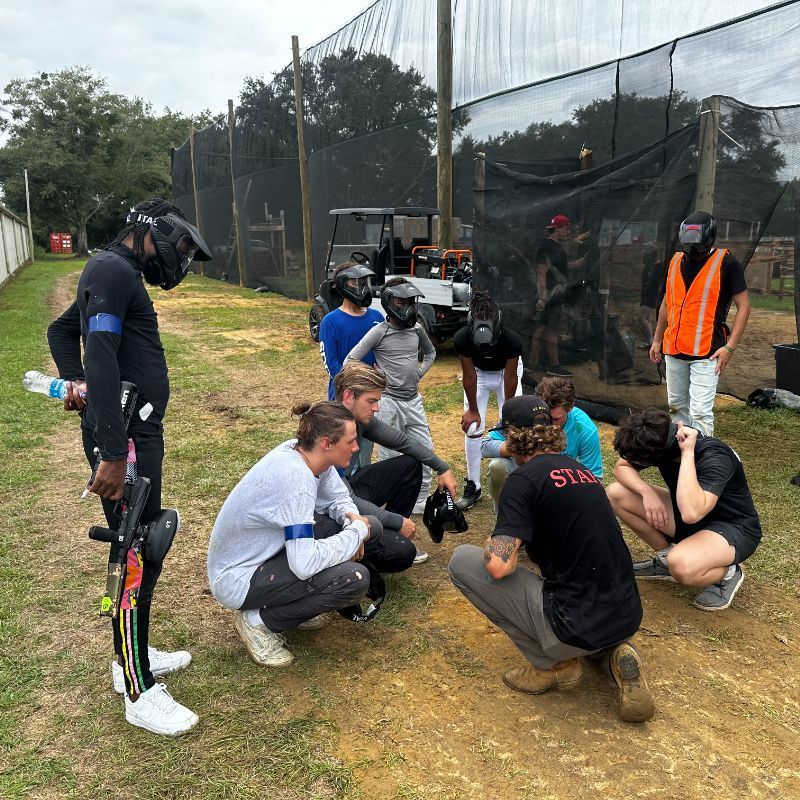 A group of paintball players are sitting on a truck and shaking hands.