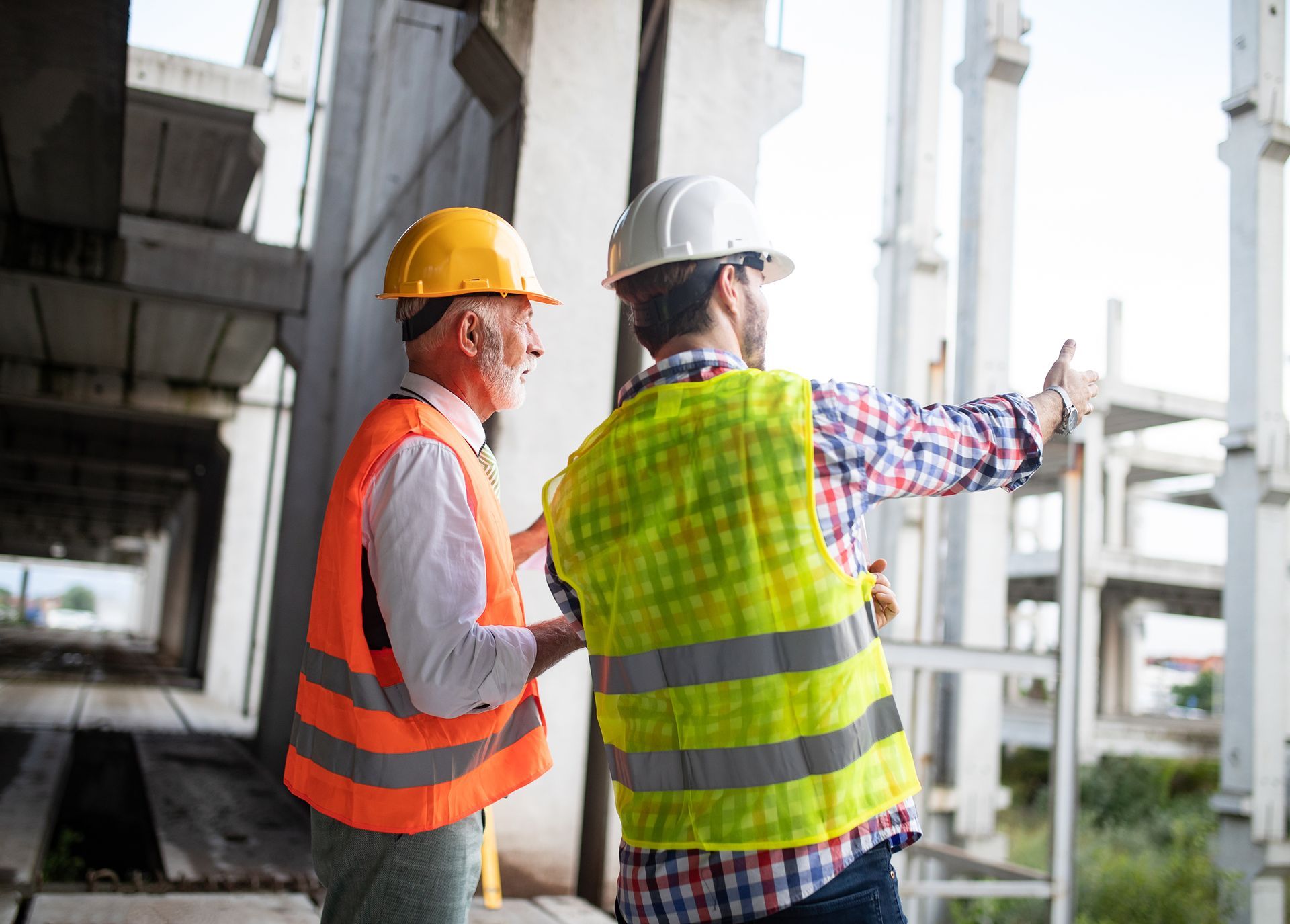 Two construction workers are standing next to each other on a construction site.