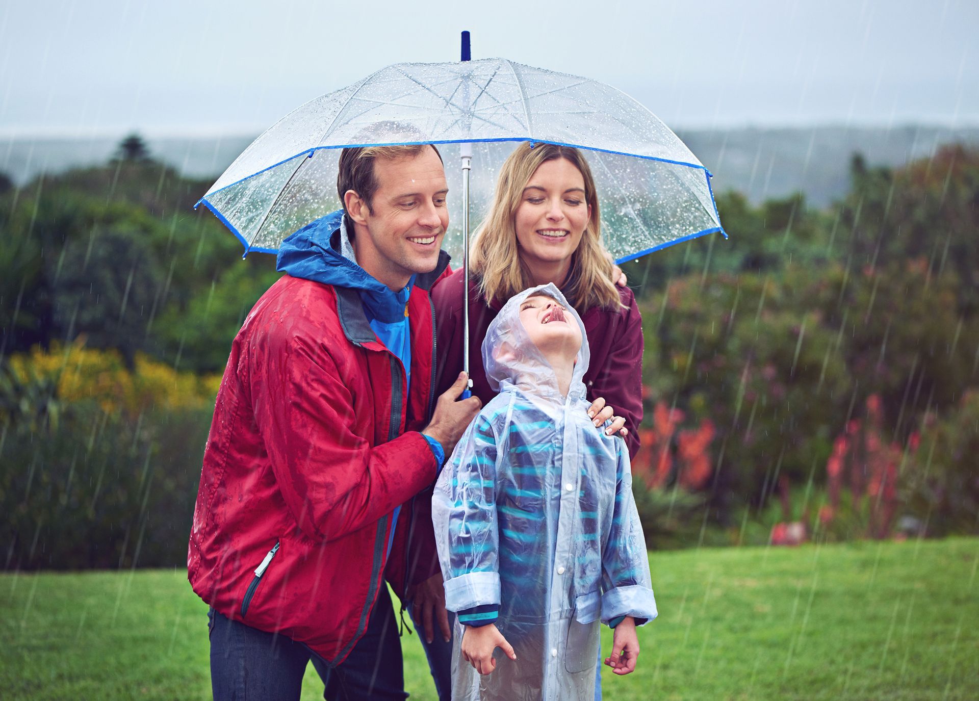 A family is standing under an umbrella in the rain.