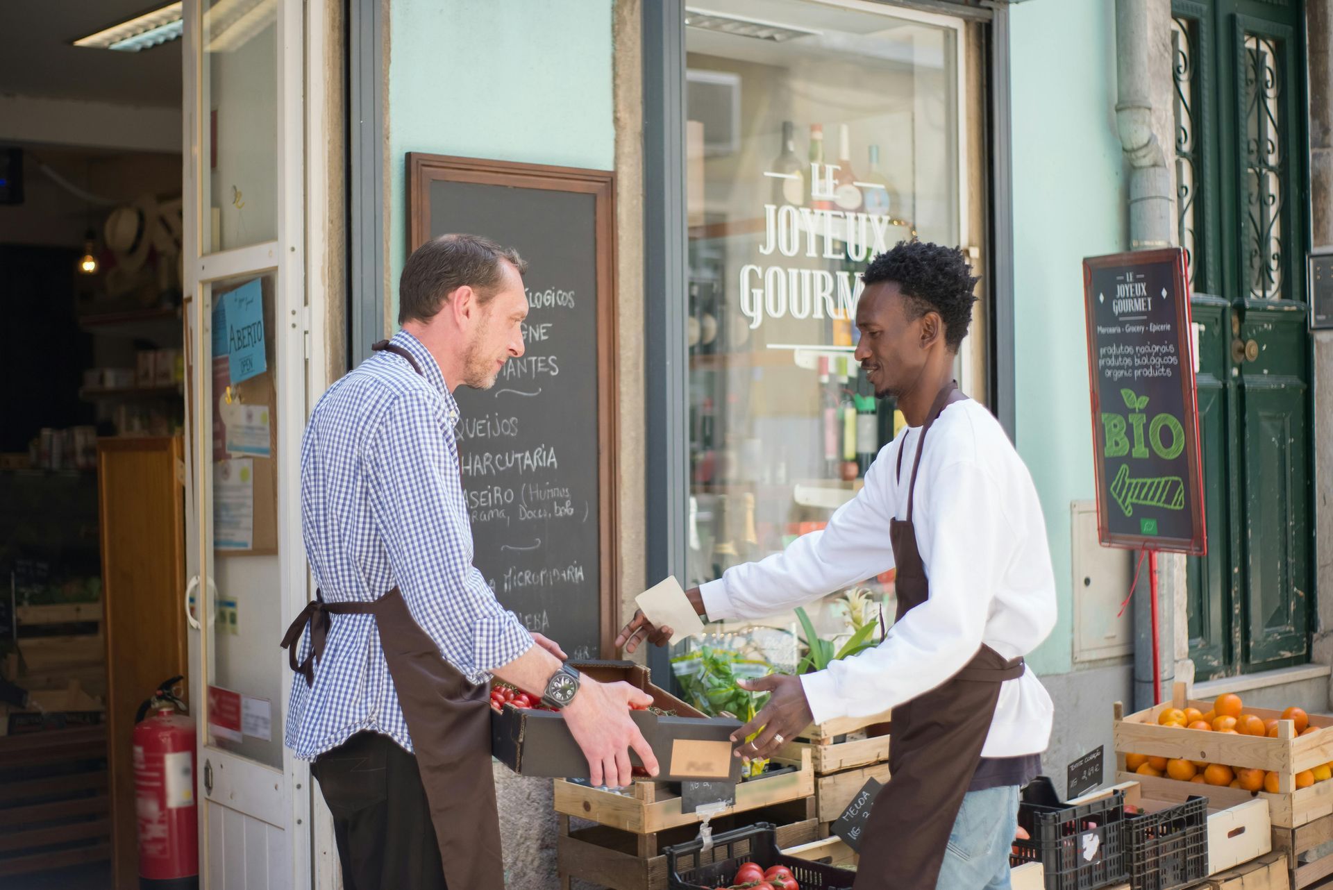 Two men are standing outside of a store talking to each other.