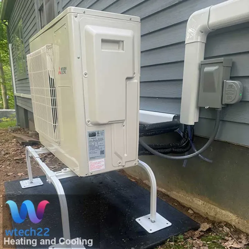 A beige heat pump unit mounted outside a house on a white metal stand.