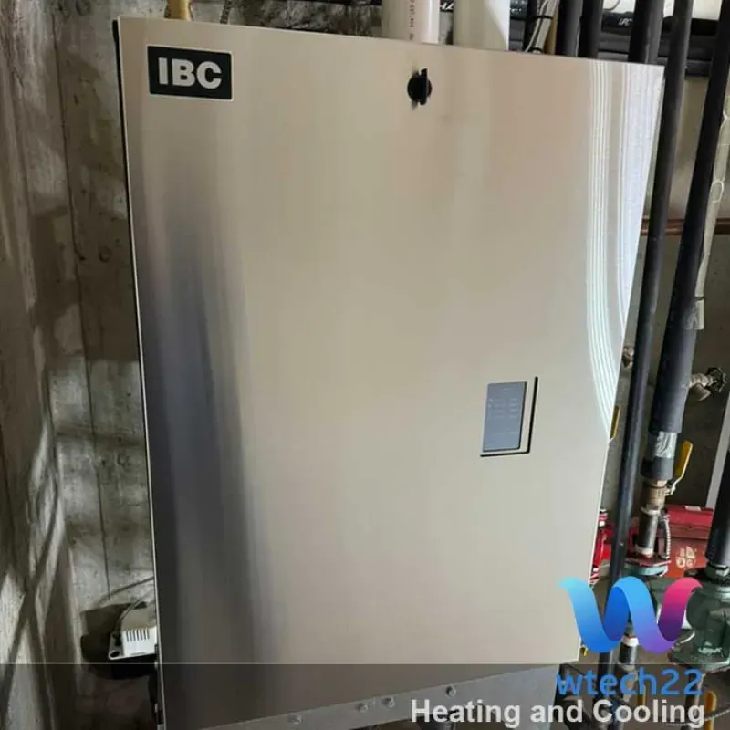 An IBC heating unit against a basement wall with pipes, wires, and a vent.
