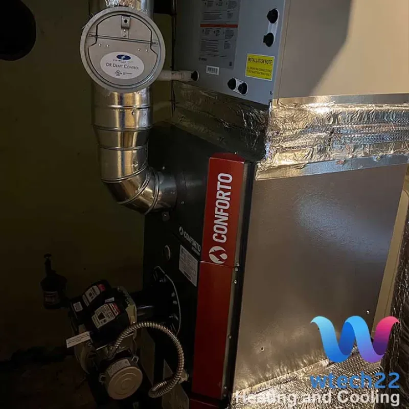 Furnace with ductwork. Silver metal, black, and red components in a utility room. 