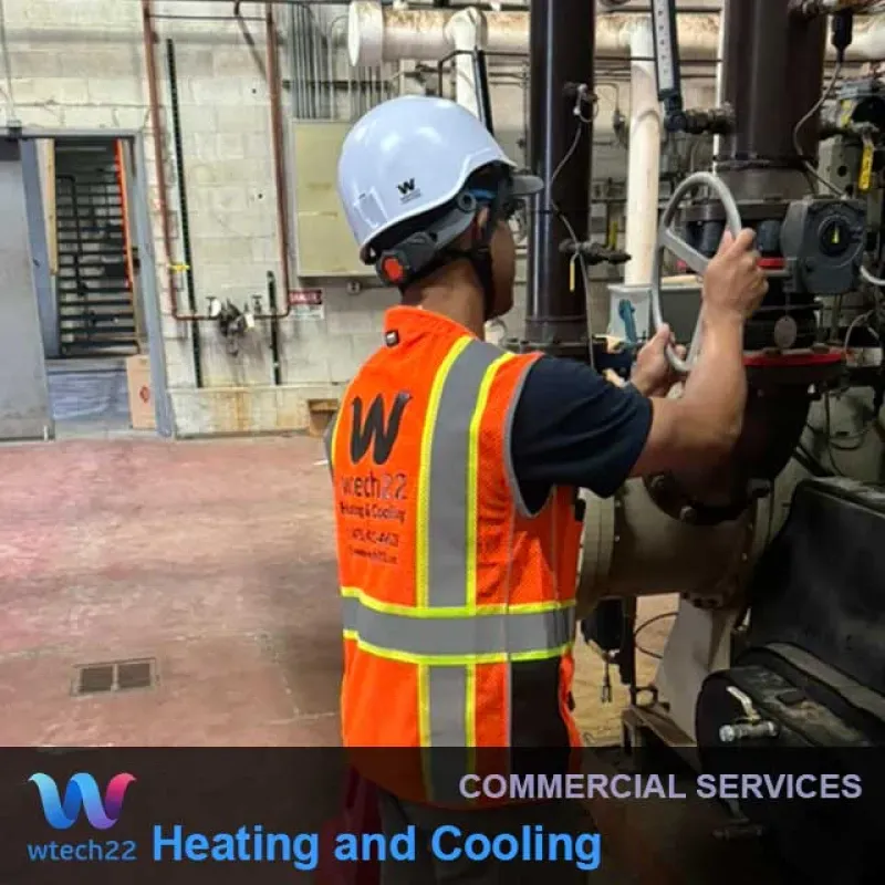 Person in a hard hat and vest adjusting machinery in an industrial setting.