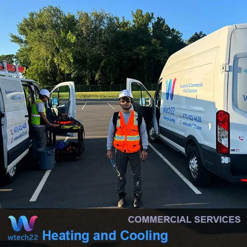 Two HVAC technicians standing by their service vans in a parking lot.