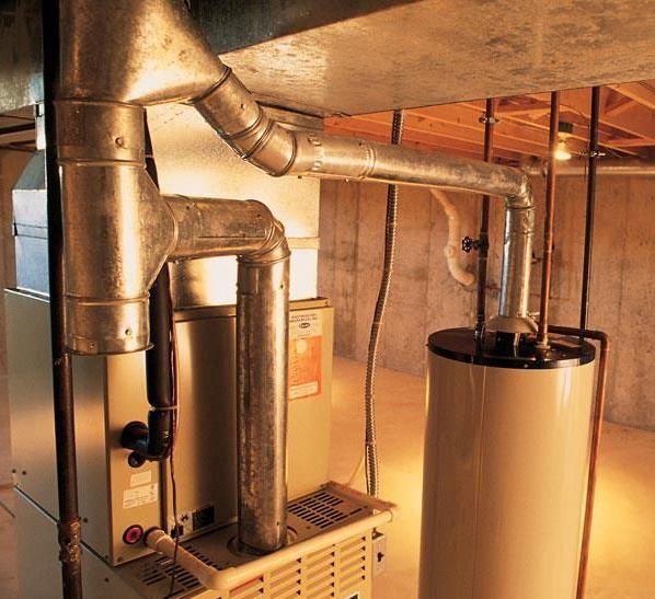 Furnace and water heater in a basement with metal ductwork and exposed wooden beams.
