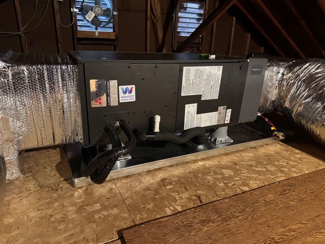 An air conditioner unit outside a house is being serviced with gauges and vacuum pump.