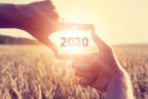 A person is holding a card with the year 2020 written on it.
