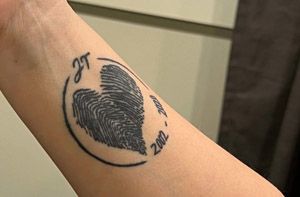 A close up of a person 's wrist with a tattoo of a heart and wings.