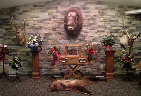 There is a bear laying on the floor in front of a stone wall.