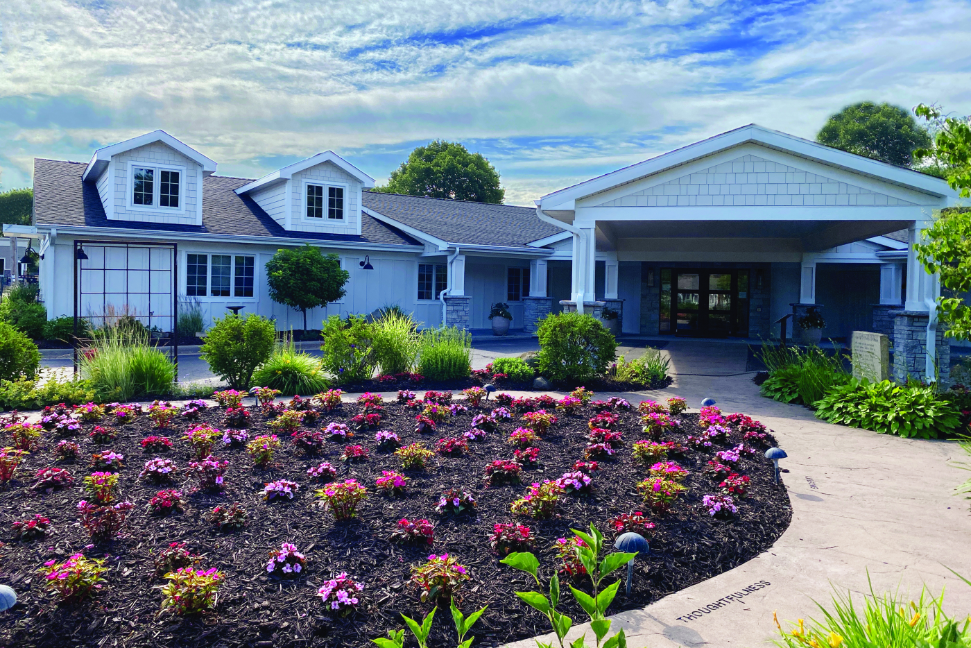 A large white house with a lush green garden in front of it.