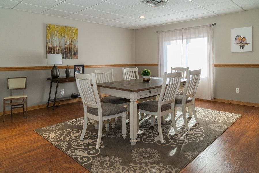 A dining room with a table and chairs and a rug.